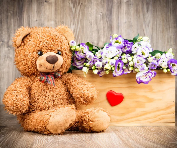 Bloemen en een teddybeer op houten achtergrond — Stockfoto