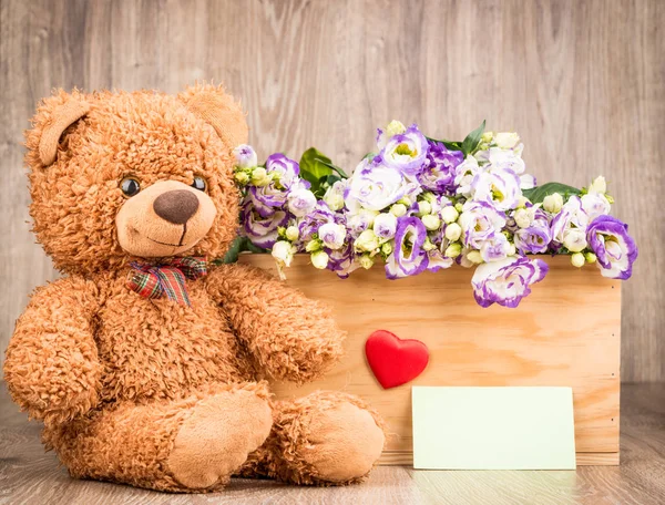 Flowers and a teddy bear on wooden background — Stock Photo, Image
