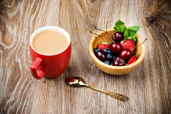 Mug of coffee and berries on wooden background — Stock Photo, Image