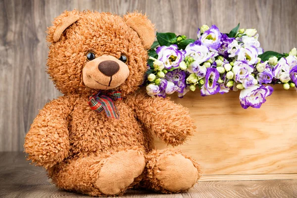 Bloemen en een teddybeer op houten achtergrond — Stockfoto