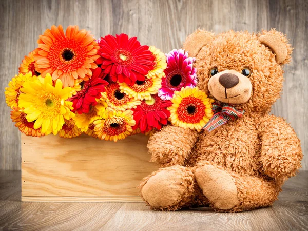 Bloemen en een teddybeer op houten achtergrond — Stockfoto