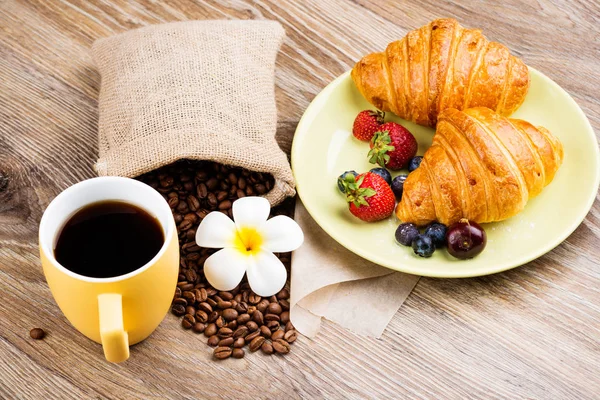 Šálek kávy a croissanty na dřevěné pozadí — Stock fotografie