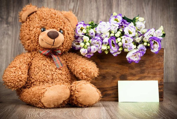 Bloemen en een teddybeer op houten achtergrond — Stockfoto