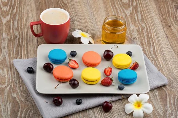 Macaroons and berries on wooden background — Stock Photo, Image