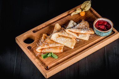 Pudra şekeri ve reçel ahşap oyun tahtası ile krep. Karanlık tablo boş alanı. Maslenitsa, Rus karnaval