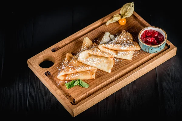 Pudra şekeri ve reçel ahşap oyun tahtası ile krep. Karanlık tablo boş alanı. Maslenitsa, Rus karnaval