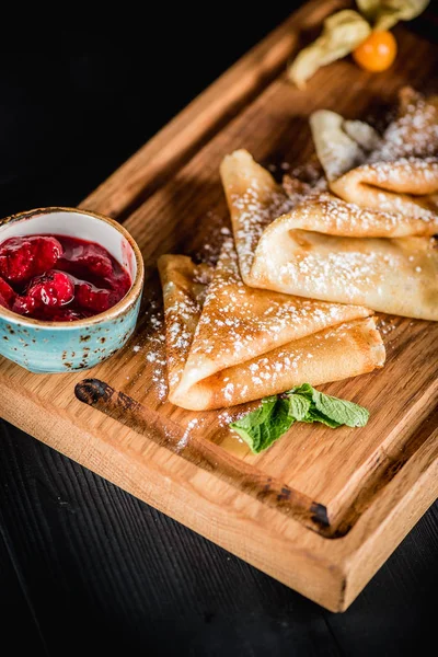 Pudra şekeri ve reçel ahşap oyun tahtası ile krep. Karanlık tablo boş alanı. Maslenitsa, Rus karnaval