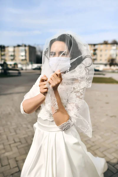 Coronavirus salgını sırasında şehrin caddesinde maske takan gelin. Düğün günü COVID-19 koruması