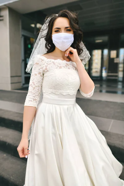 Coronavirus salgını sırasında şehrin caddesinde maske takan gelin. Düğün günü COVID-19 koruması 