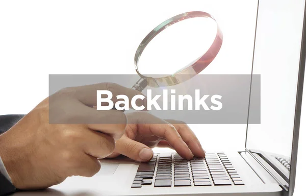 Mão segurando lupa vidro com palavra Backlinks — Fotografia de Stock