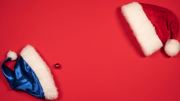 新年のボールとサンタクロースの帽子の動きのアニメーションを停止します クリスマスボールと赤と青の帽子のフラットレイアウト トップ表示 — ストック動画