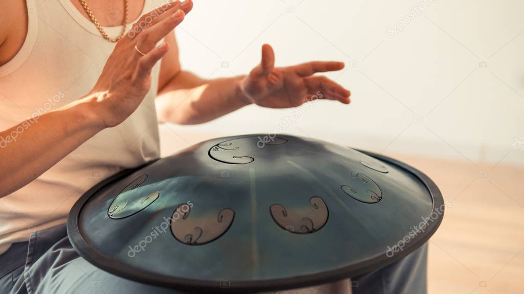 Close up of man hands playing hang drum indoors. Unusual music i