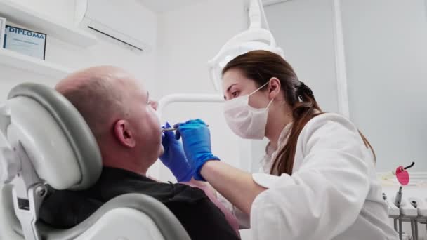女牙医使用消毒设备进行检查和手术 坐在牙椅上的男病人 牙科护理和诊所概念 — 图库视频影像