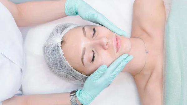 Женщина-дерматолог делает массаж лица красивой девушке — стоковое фото