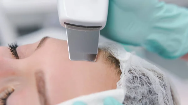 Kadın kozmetik uzmanı ultrasonik temizlik prosedürü uyguluyor.