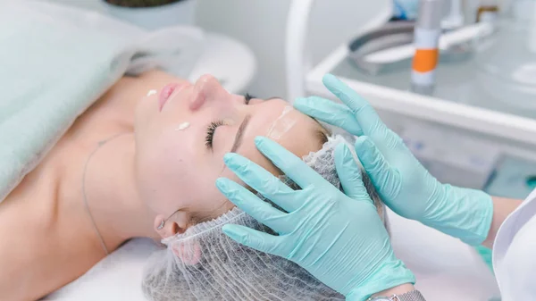 La dermatóloga hembra hace masajes faciales a la hermosa chica cosm — Foto de Stock