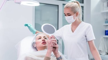 Genç güzellik uzmanı kadın dudaklarına iğne yapmaya hazırlanıyor. Doktor kozmetik uzmanı dudak büyütme prosedürü uyguluyor. Güzellik salonu ve estetik cerrahi kliniği kavramı.