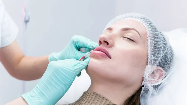 stock image The young beautician doctor preparing to making injection in female lips. The doctor cosmetologist makes lip augmentation procedure. Concept of beauty salon and plastic surgery clinic.