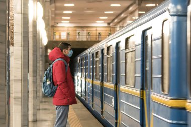 Metroda tek kullanımlık koruyucu maskeli genç Avrupalı adam. Yeni koronavirüs (Covid-19). Salgın veya salgın sırasında sağlık hizmeti kavramı