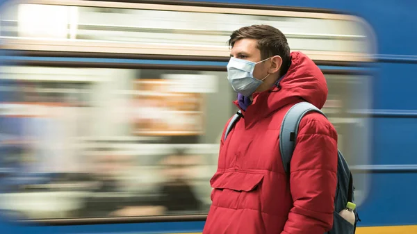 The young europeans man in protective disposable medical face mask in the subway. New coronavirus (COVID-19). Concept of health care during an epidemic or pandemic