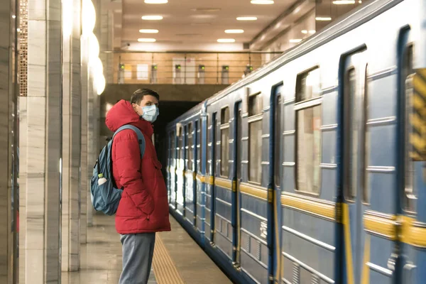 Metroda tek kullanımlık koruyucu maskeli genç Avrupalı adam. Yeni koronavirüs (Covid-19). Salgın veya salgın sırasında sağlık hizmeti kavramı
