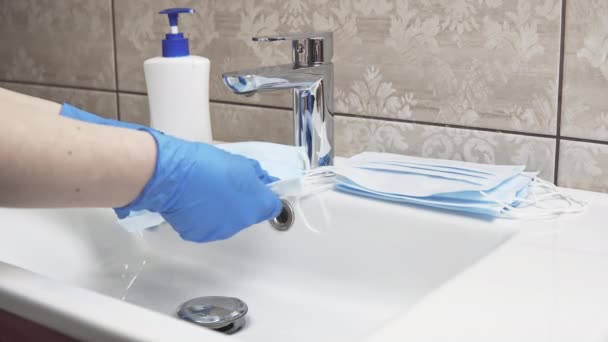 石鹸で使い捨ての医療用フェイスマスクを洗う女性の手のクローズアップ 流行やパンデミックの際のパーソナルケア製品の欠陥 医療の概念 — ストック動画