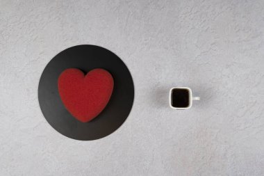 Kadife kek kalp şeklinde ve bir fincan kahve, düz. Çikolata kadifeli modern Fransız kremalı pasta. Şekerleme ve kafe kavramı.