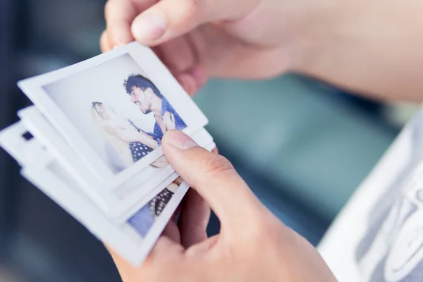 Close-up of man holding in the hand printed photos with picture of young couple. Concepts of happy memories, romantic and love