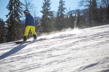 Dağda güneşli güzel bir gün, snowboardcu aşağı iner.