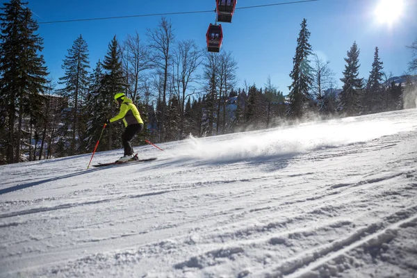 In una mattina di sole sulla montagna, uno sciatore in giacca gialla g — Foto Stock