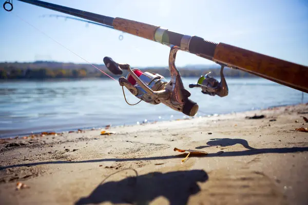 Fish fishing rods are on the sandy beach on the river. We're wai — Stock Photo, Image
