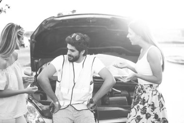 Yakışıklı sakallı adamın yolda bozuk bir arabası var. İki güzel genç kadın ona yardım etmek için uğradı ve iyi vakit geçirdiler. Sakallı adam bozuk arabayı unuttu. Siyah beyaz fotoğraf galerisi.