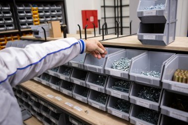 Adamın eli raftaki uygun vidaları arıyor. Tornavida ve inşaat malzemeleri dükkanında.