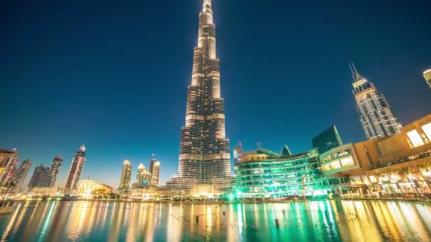 Fuente de baile Timelapse cerca de Burj Khalifa iluminado por la ciudad por la noche. Burj Khalifa es la estructura artificial más alta del mundo — Vídeo de stock