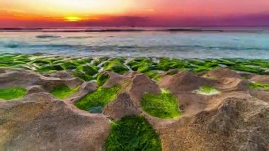Endonezya Bali Adası yosun kaplı donmuş volkanik huniler ile Balangan sahilde günbatımı Timelapse.