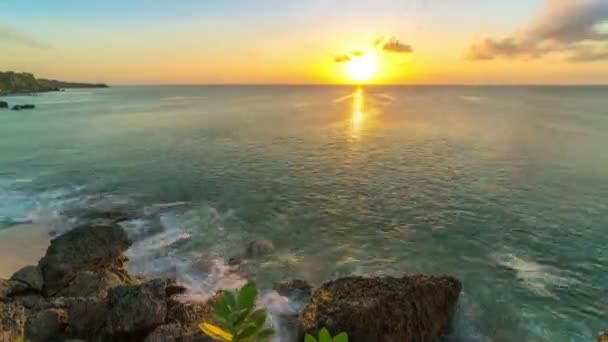 Timelapse du coucher de soleil sur la plage de l'île de Bali en Indonésie, au fond des vagues se brisent contre les rochers . — Video