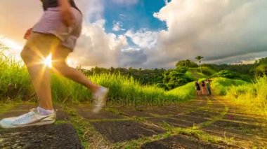 Gün batımı timelapse ve insanlar Campuhan Ridge yürümek, yol üstünde tepe-in çimenli tepe üzerinde yürümek. Gianyar Regency Bali Ubud popüler trekking yerde. Ubud, Endonezya - Jule, 2017