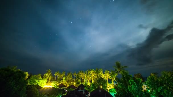 Cielo nocturno con estrellas sobre la selva tropical, palmeras y bungalows en la isla de Bali en Indonesia . — Vídeo de stock