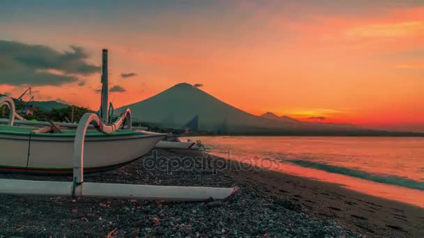 Západ slunce s výhledem na sopka Agung na pozadí rybářského člunu na zátoky beach Jemeluk v Amedu na ostrově Bali v Indonésii. — Stock video
