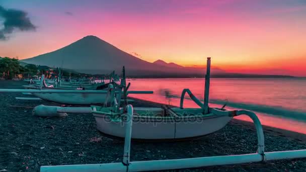 Západ slunce s výhledem na timelapse sopka Agung na pozadí rybářské lodě na pláži Djemeliuk v Amedu na ostrově Bali v Indonésii. — Stock video
