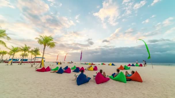 Timelspae Les gens se couchent sur une plage blanche sur des oreillers et rencontrent le coucher du soleil sur l'île de Nusa Lembongan, Bali, Indonésie. Août 2017 — Video