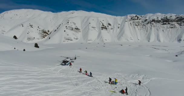 Σκιέρ και snowboarders επιβιβαστεί σε ελικόπτερο στα βουνά το χειμώνα. Εναέρια άποψη, κάμερα μετακίνηση προς τα εμπρός. — Αρχείο Βίντεο