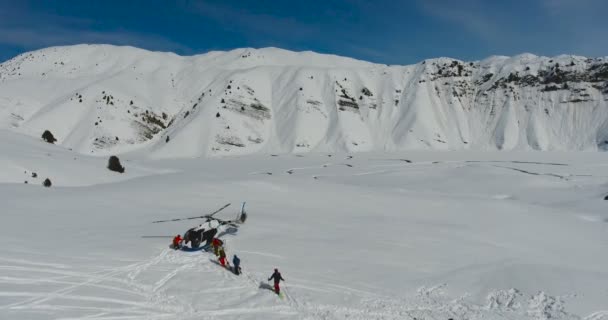 Sciatori e snowboarder salgono a bordo di un elicottero sulle montagne invernali. Vista aerea, fotocamera scorrevole verso il basso . — Video Stock