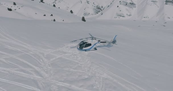 Antennen flyger över ett parkerade helikopter stående i snön i vinter bergen — Stockvideo