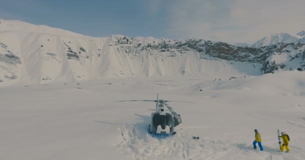 Flygfoto skidåkare gå till helikoptern i de snötäckta bergen — Stockvideo