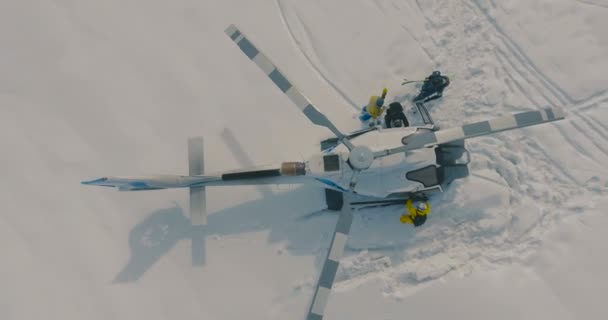 Sciatori che salgono su un elicottero da elisci in piedi sulla neve. La vista aerea dall'alto e la fotocamera si muovono verso l'alto . — Video Stock