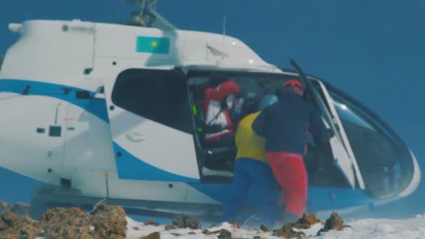 Skidåkare och snowboardåkare är iland från helikoptern i bergen på vintern. Nära håll view. — Stockvideo