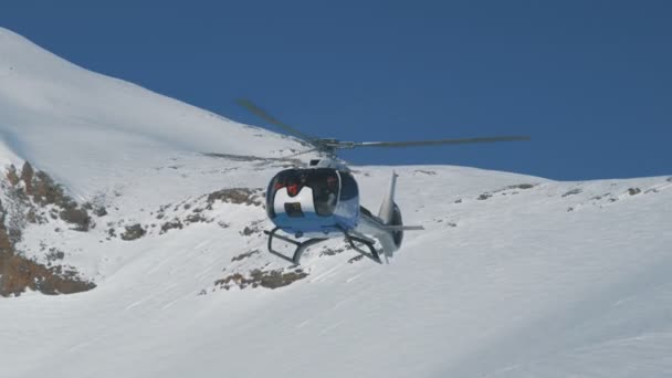 Белый вертолет приземляется крупным планом на фоне зимних гор. Тянь-Шань, Шымкент, Казахстан - февраль 2018 года — стоковое видео