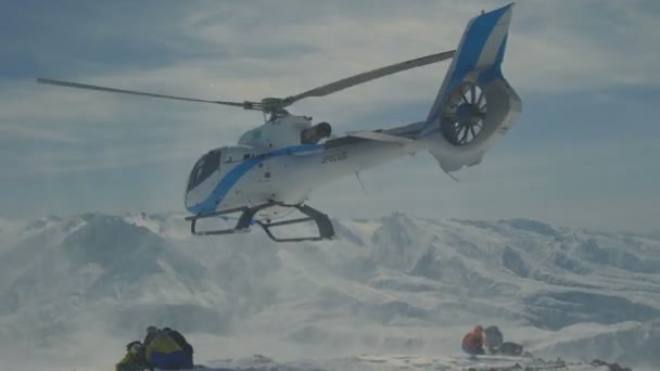 Der Helikopter ließ Skifahrer am Hang des Berges zurück und flog eine Schneewolke empor — Stockvideo