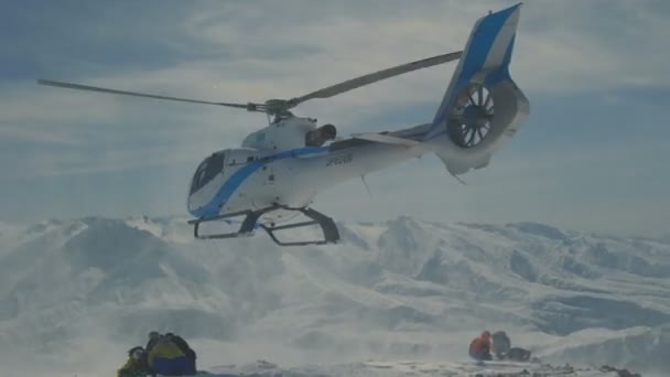 L'hélicoptère a laissé les skieurs sur la pente de la montagne et a volé en soulevant un nuage de neige — Video